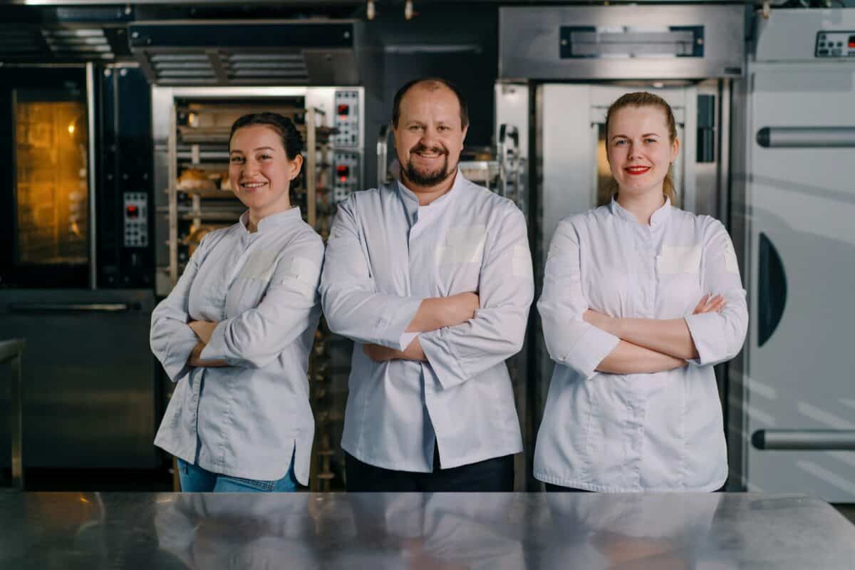 a team of smiling professional bakers in a professional kitchen in a bakery