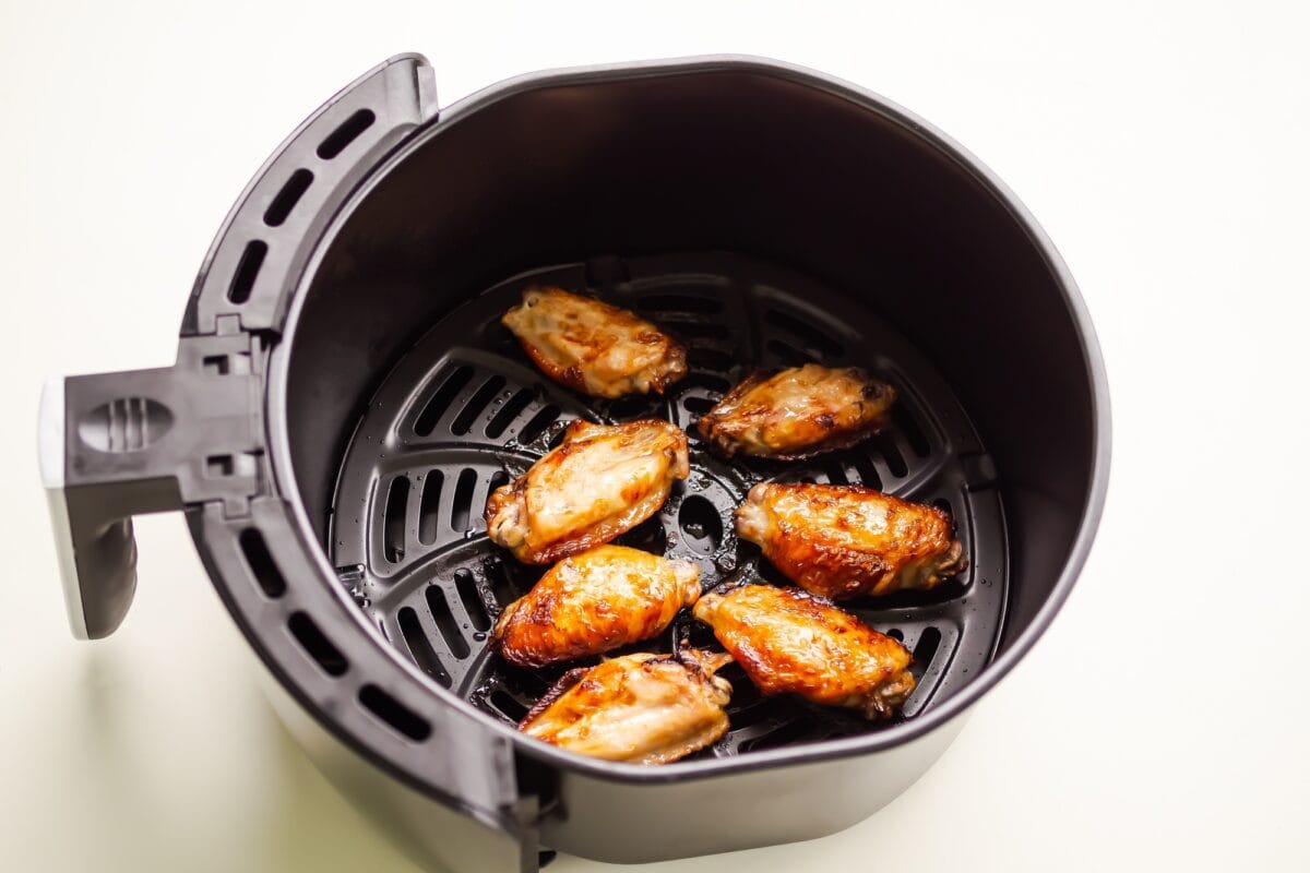Ailes de poulet cuites dans une friteuse à air comprimé sur fond de table blanche.