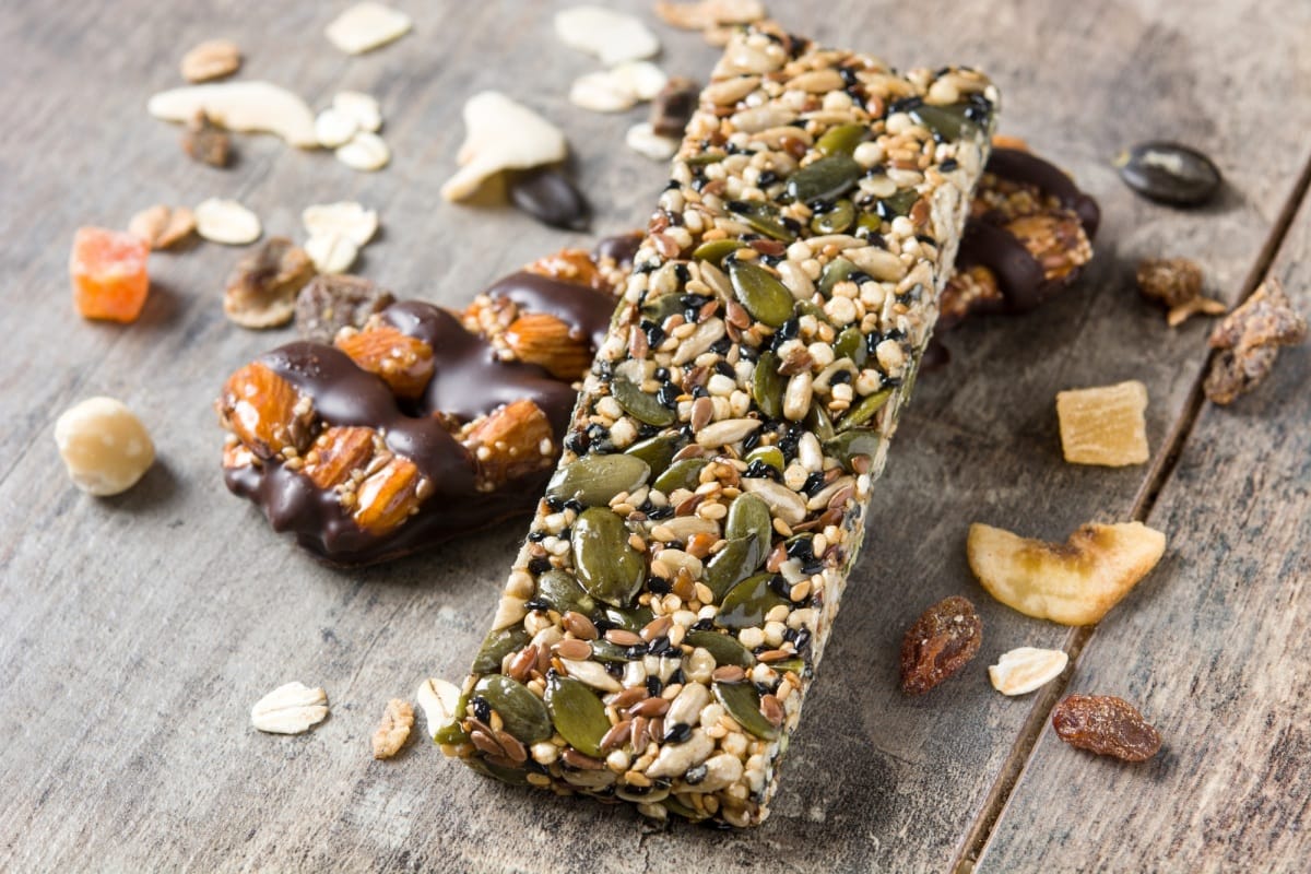 Barres protéinées avec noix, graines, chocolat et fruits secs sur une table en bois
