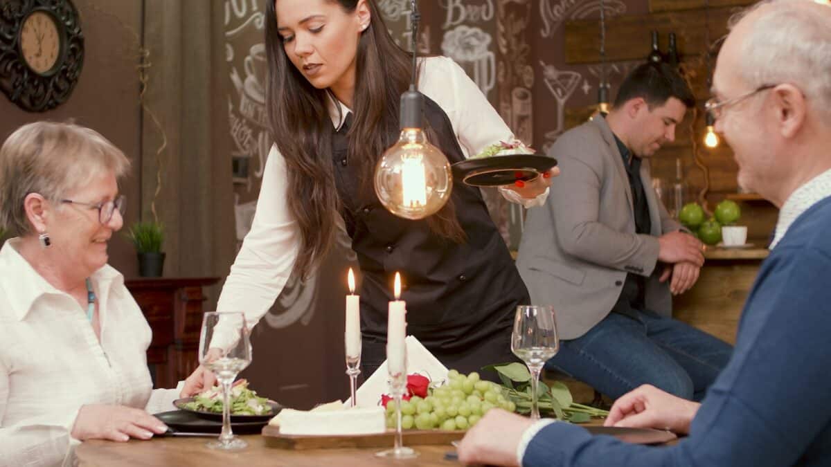 Beautiful waiter serving a beautiful senior couple in a restaurant