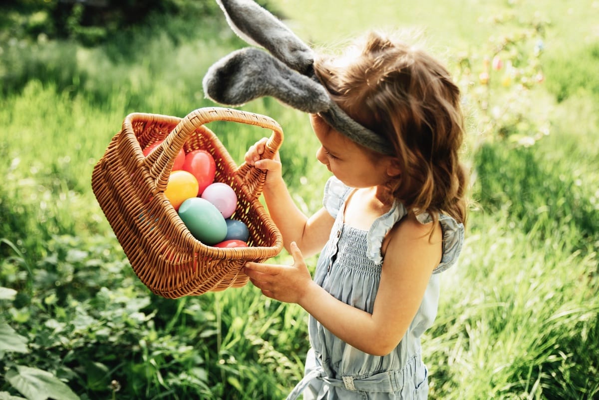 Bébé avec un panier rempli d'oeufs colorés. Chasse aux œufs de Pâques