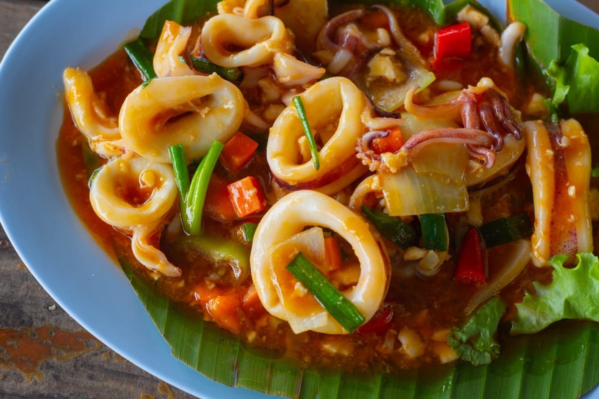 Calmar sauté avec œuf salé sur table en bois, gros plan.