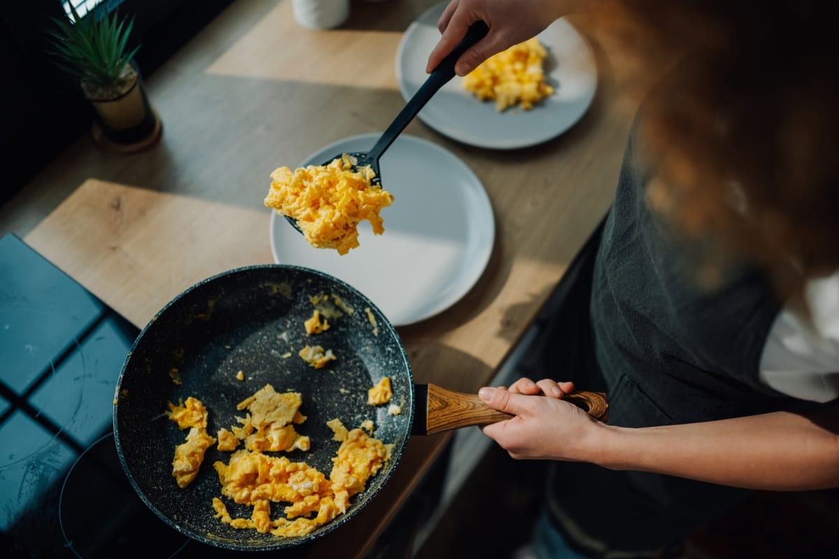 Chef servant des œufs brouillés de la poêle à frire sur une assiette