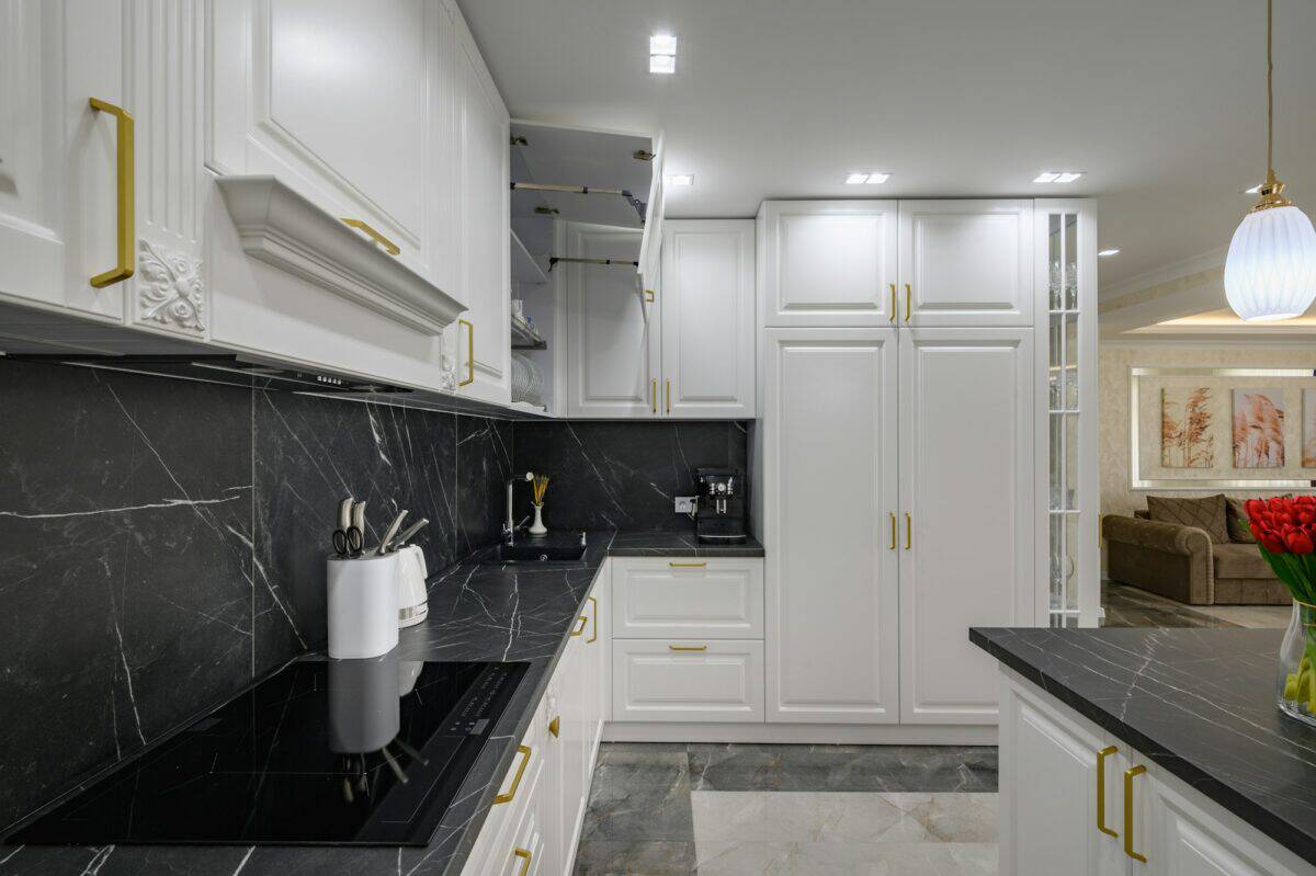 Closeup to black granite worktop of white domestic kitchen with marble floor