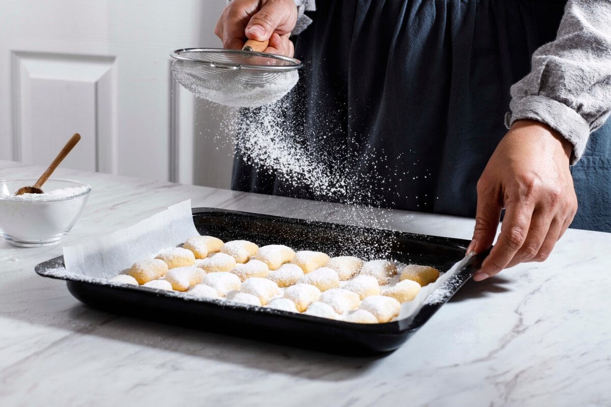 Coating vanillekipferl Cookie with Sugar Dust Using Strainer, Fresh Home Baked Christmas Cookies