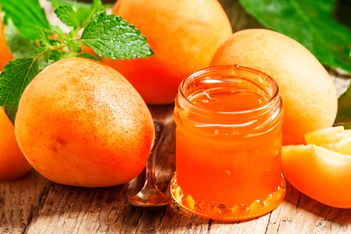Confiture d'abricots maison et abricots frais avec feuilles sur la vieille table en bois