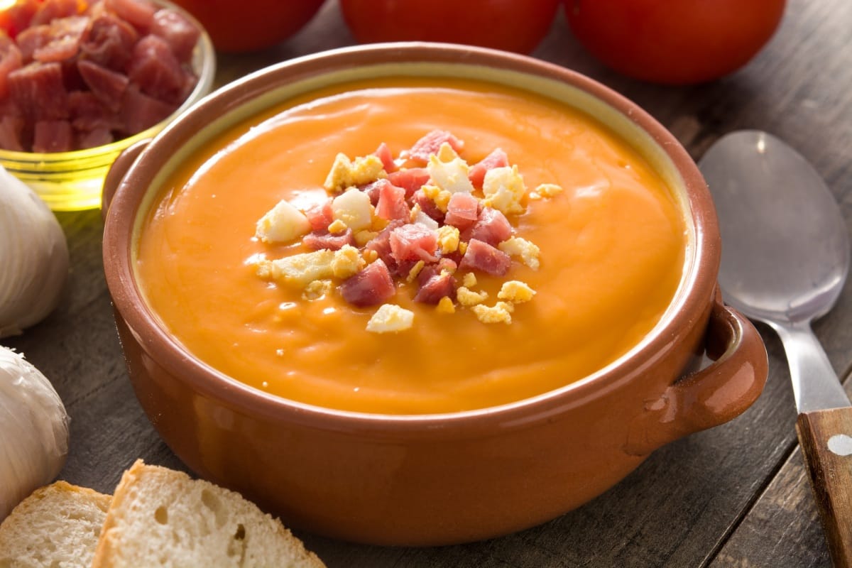 Crème salmorejo espagnole typique avec jambon et œuf sur une table en bois