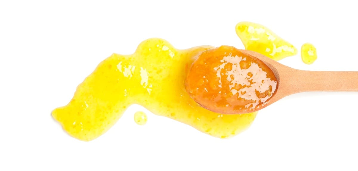 Cuillère avec confiture d'abricot isolée sur fond blanc