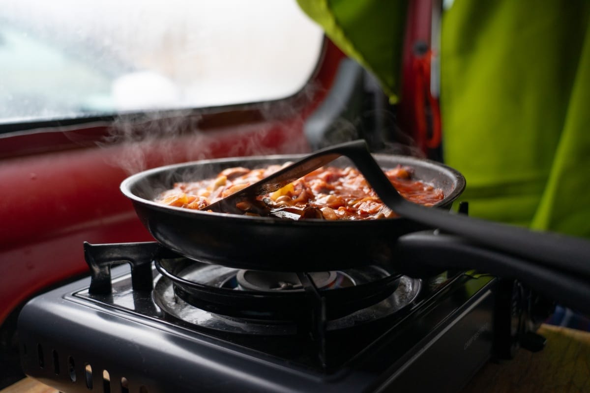 Cuisson à la poêle sur un camping-gaz dans un camping-car