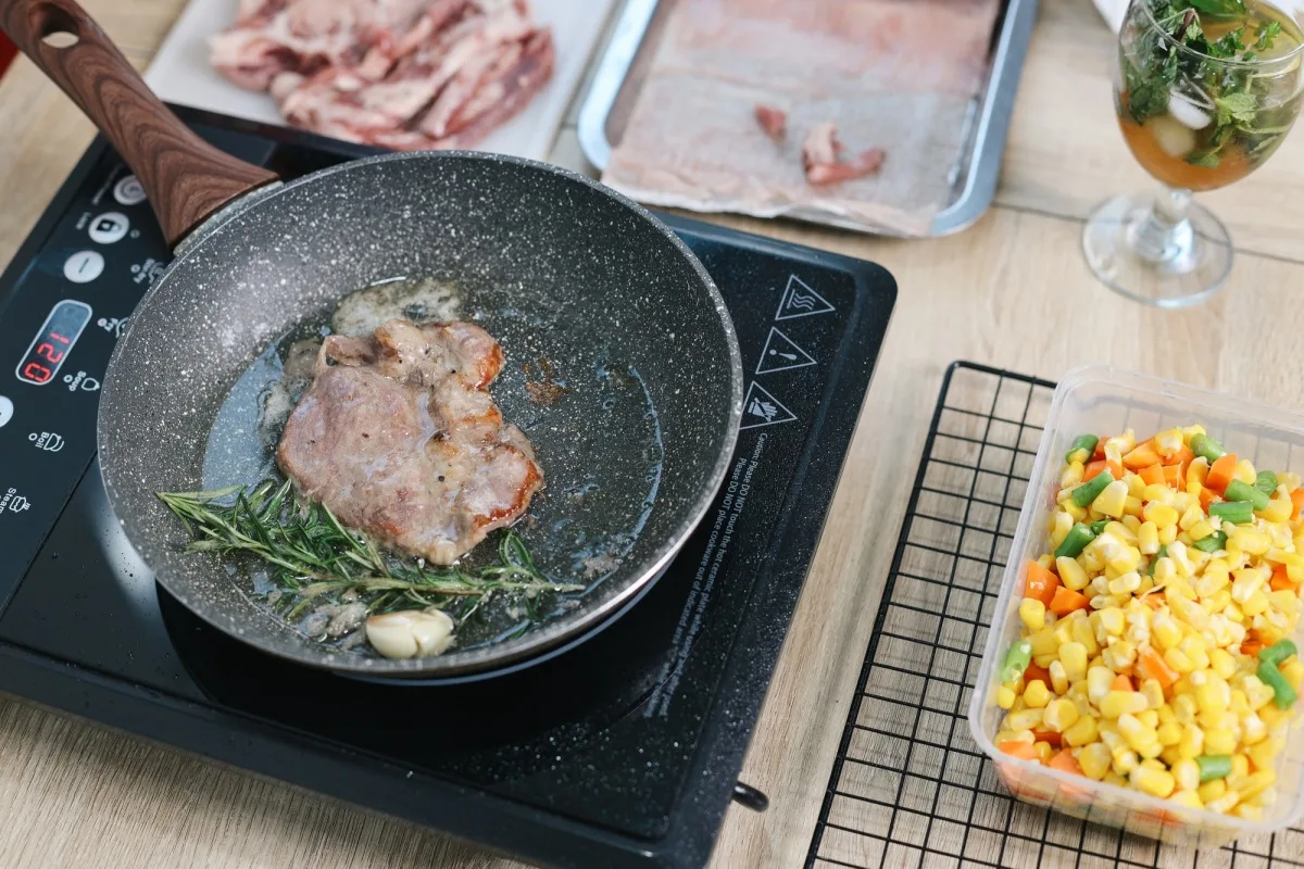 Cuisson de la viande, du romarin et de l'ail sur la cuisinière électrique