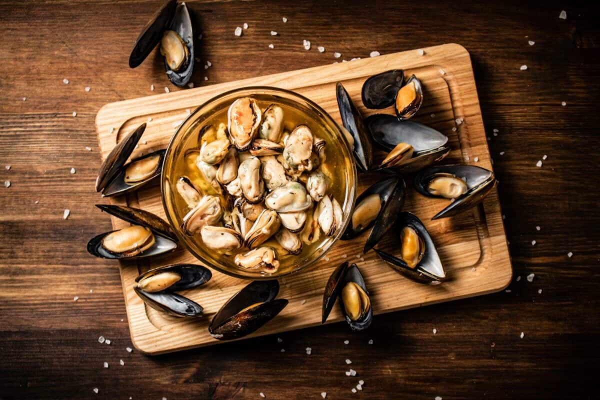 De délicieuses moules marinées dans un bol sur une planche à découper.