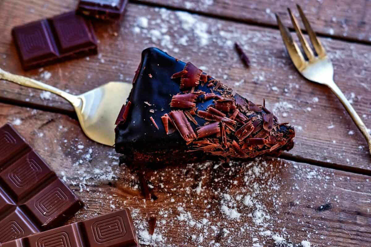 Delicious slice of chocolate cake with peaces of chocolate on dark table.