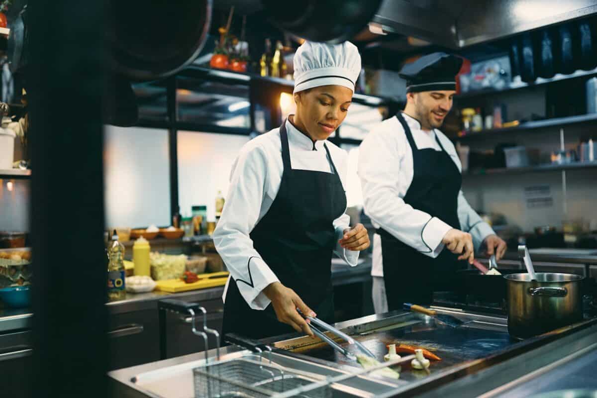 Deux cuisiniers professionnels préparent un repas dans la cuisine d'un restaurant.