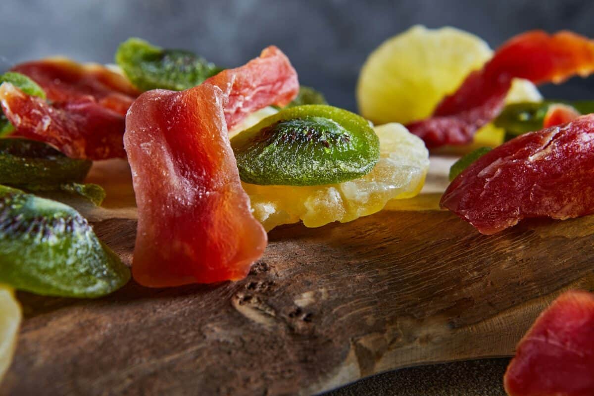 Dried fruits: Yellow candied pineapple rings, red papaya and green on a wooden cutting board