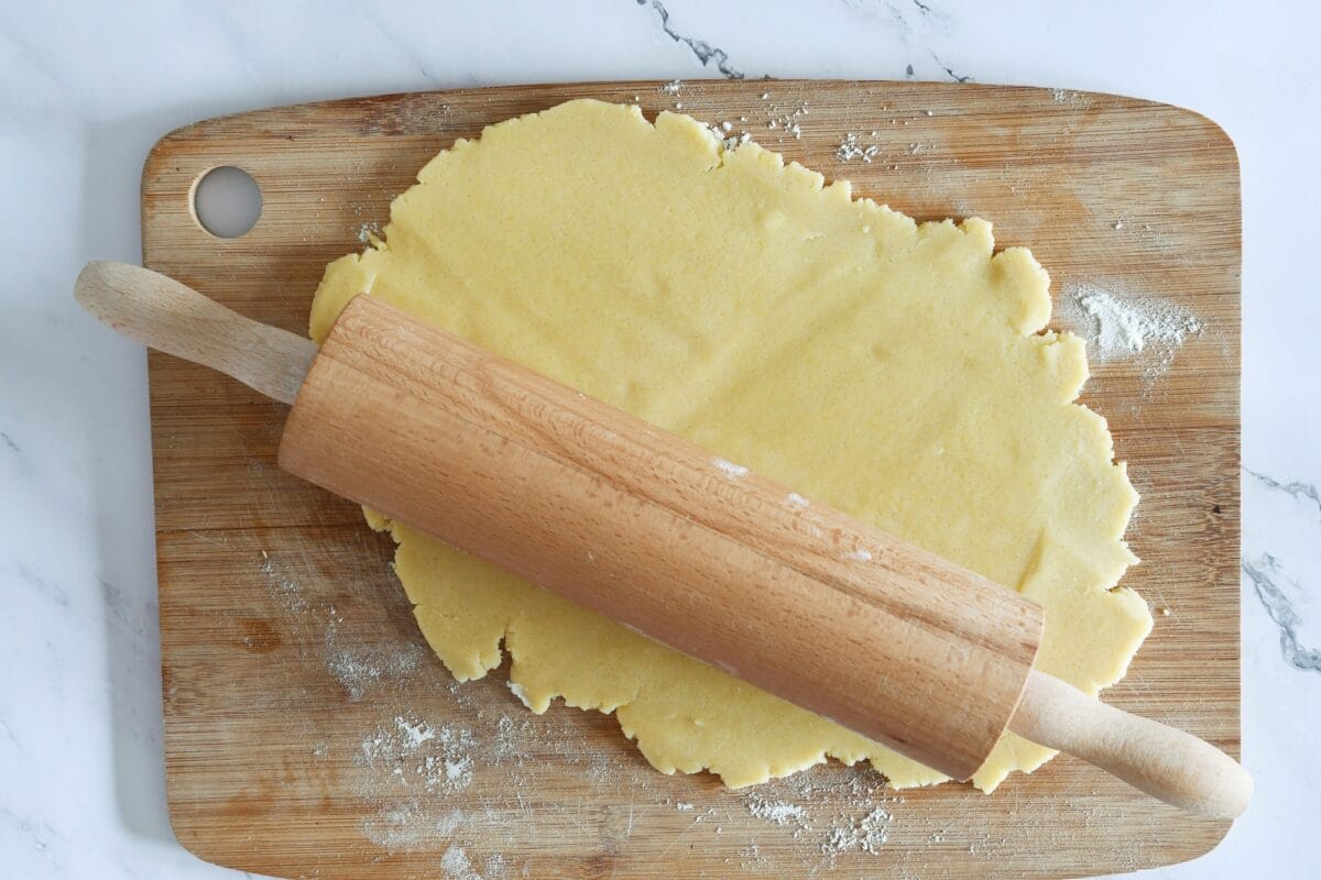 étaler la pâte brisée pour les biscuits à l'aide d'un rouleau à pâtisserie en bois