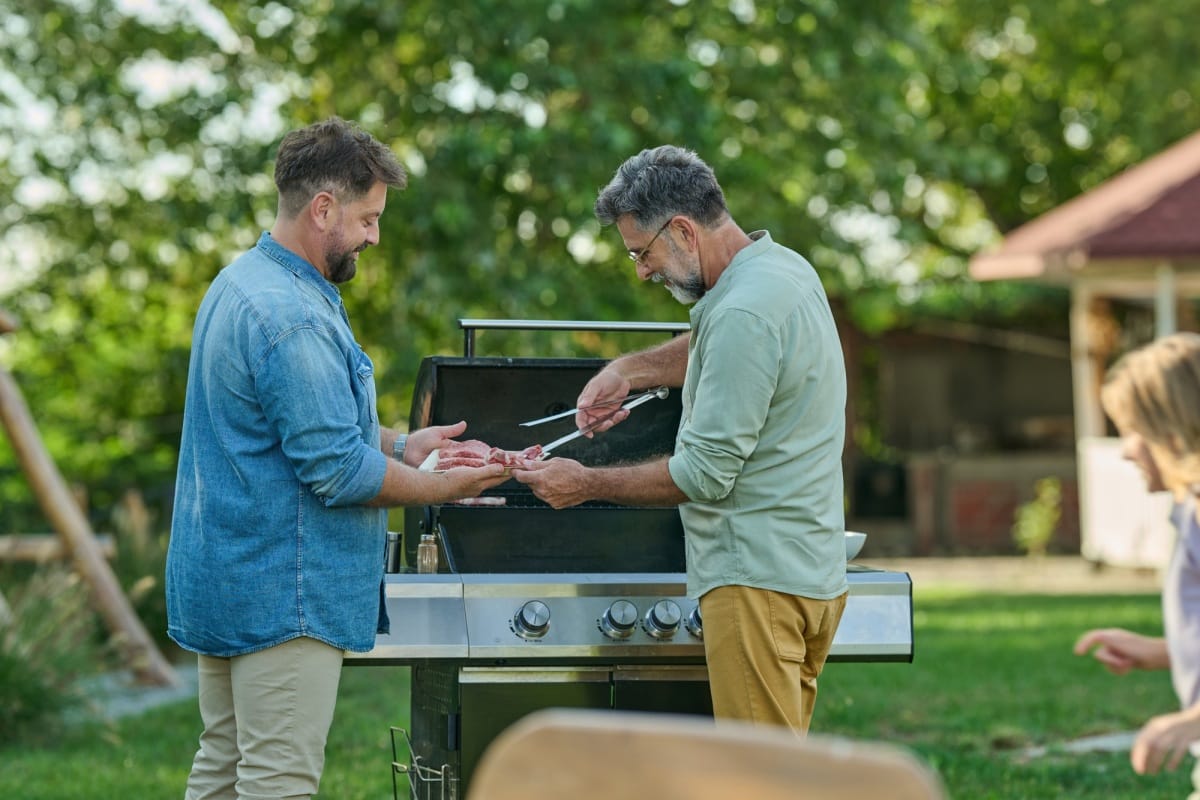 Famille préparant des aliments sur une grille de barbecue lors d'une fête dans l'arrière-cour