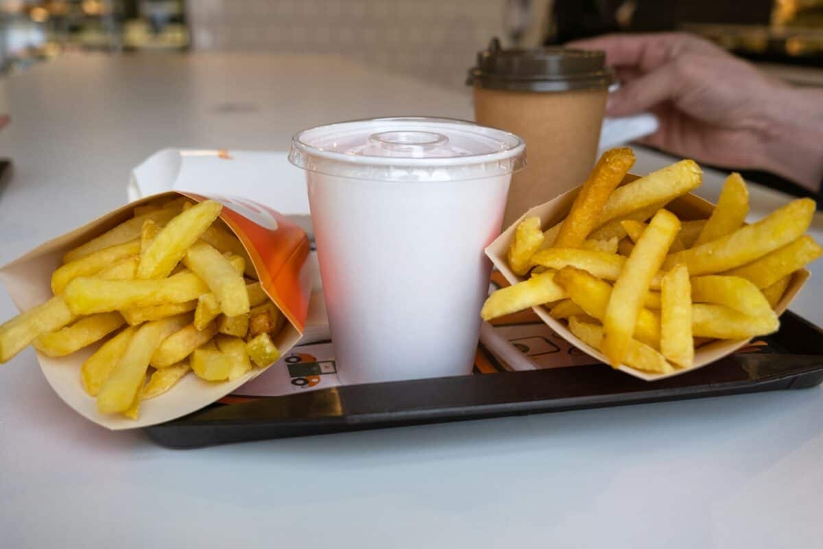 Fast food on a tray in a restaurant. French fries, a glass with a milkshake, coffee