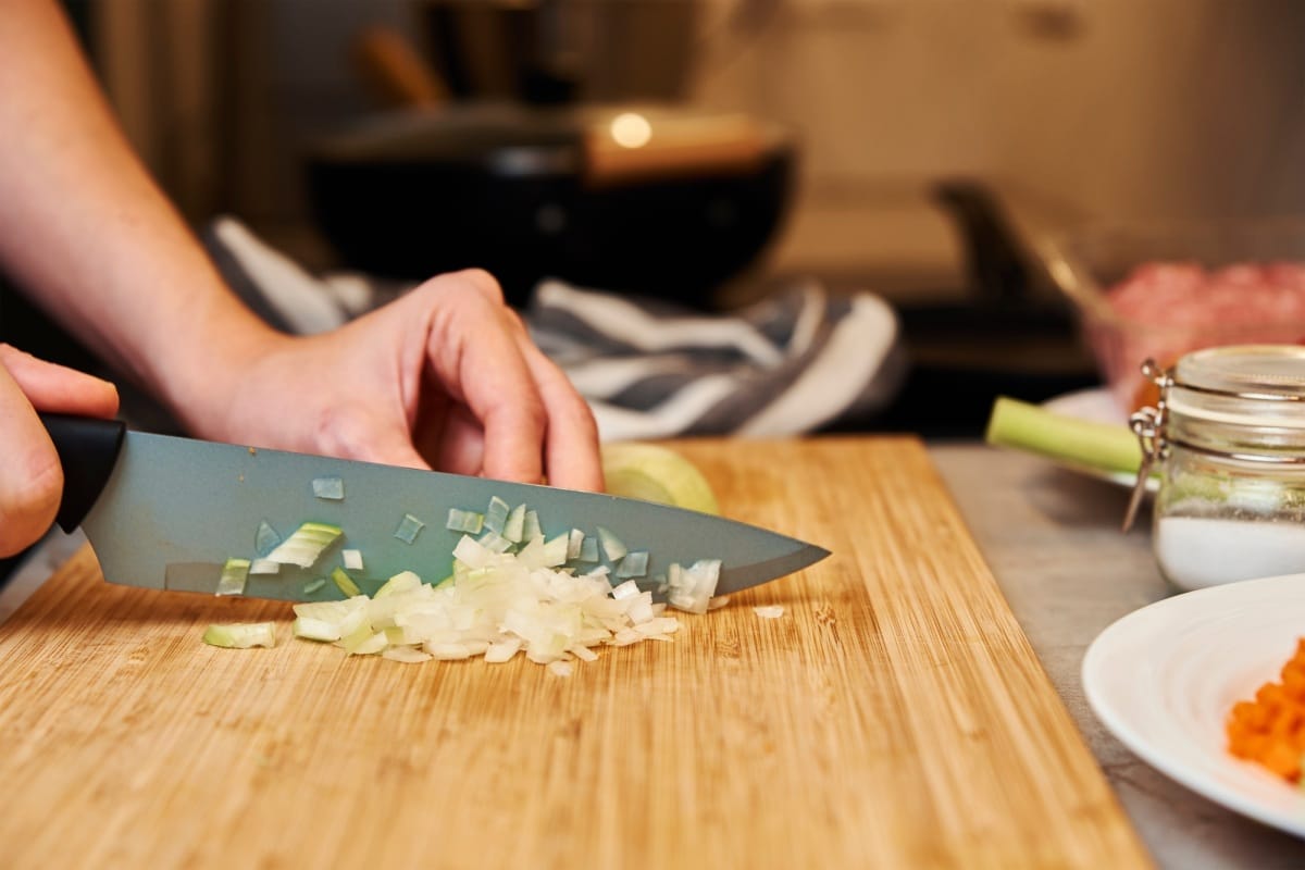 Femme coupant un oignon dans la cuisine, gros plan