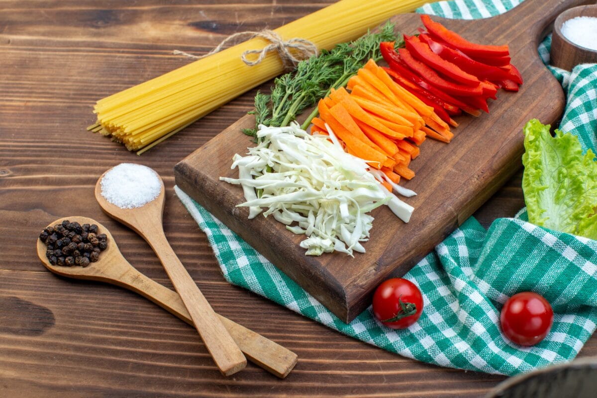 front view sliced vegetables cabbage carrot greens and pepper on cutting board brown background