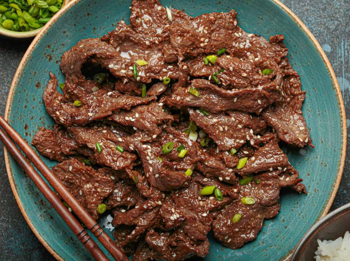 Gros plan sur un délicieux plat de bulgogi servi avec du riz et des oignons verts vue du dessus, cuisine coréenne