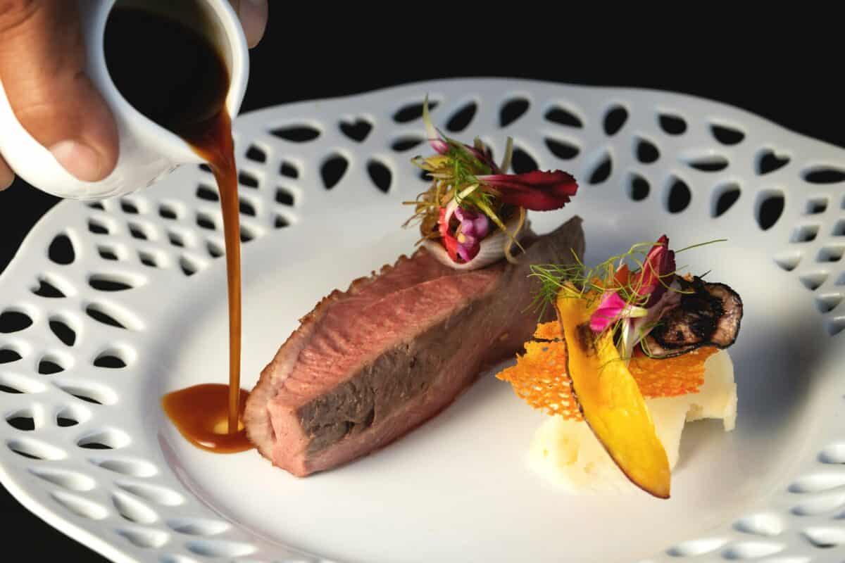half-cooked lamb meat with vegetables, petals, sweet potato chips and hand pouring gravy