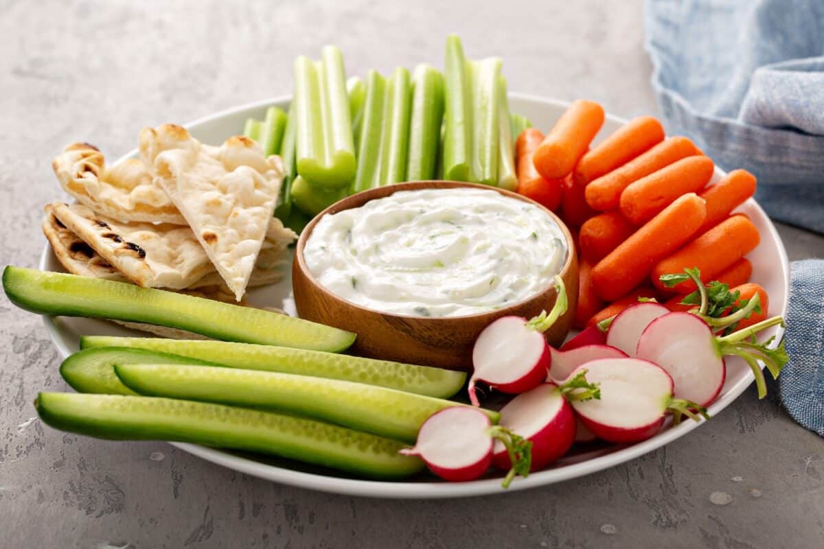 Large snack board with tzatziki dip or sauce and fresh vegetables