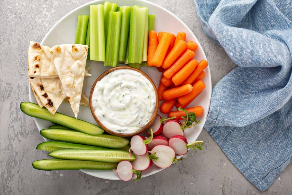 Large snack board with tzatziki dip or sauce and fresh vegetables