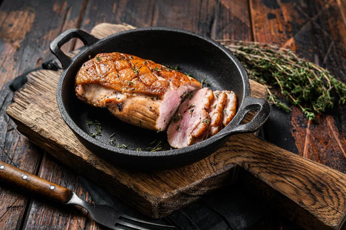 Magret de canard rôti dans une poêle, steak de viande de volaille aux herbes. Fond en bois. Vue de dessus