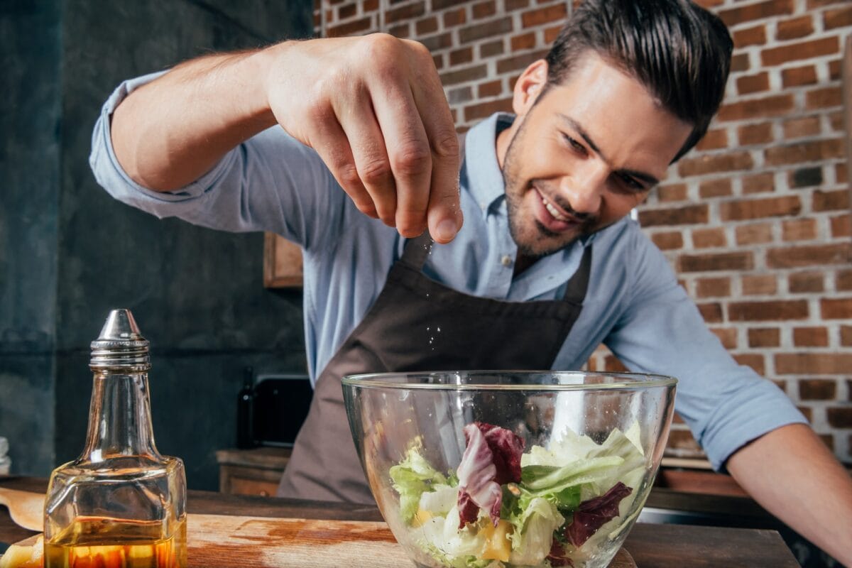 man adding salt into fresh salad