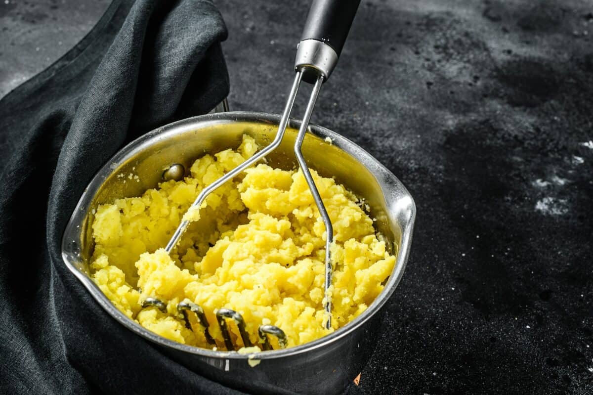 Mashed potatoes with milk and eggs in a pot. black background. top view