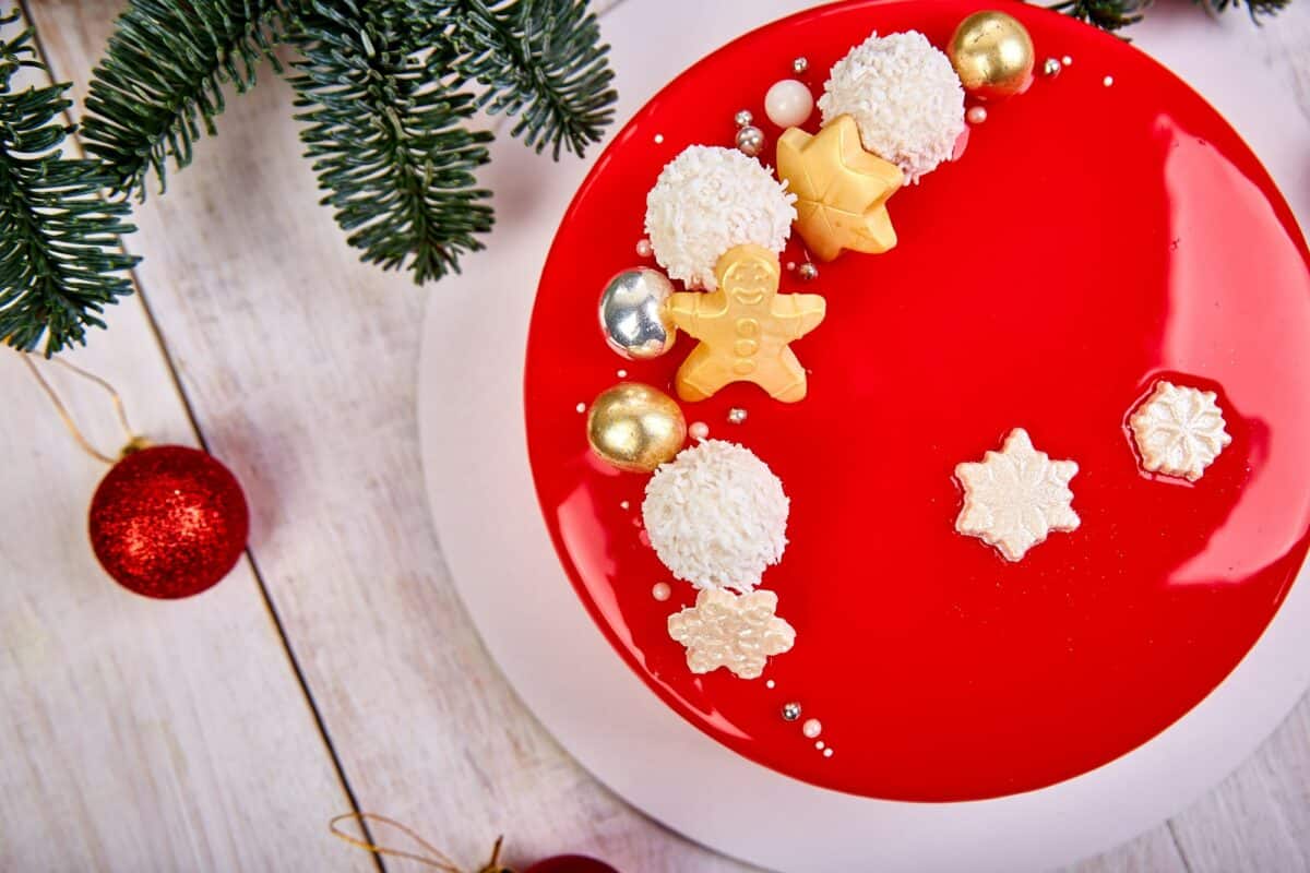 Mousse Christmas pastry cake dessert covered with red mirror glaze with new year decorations