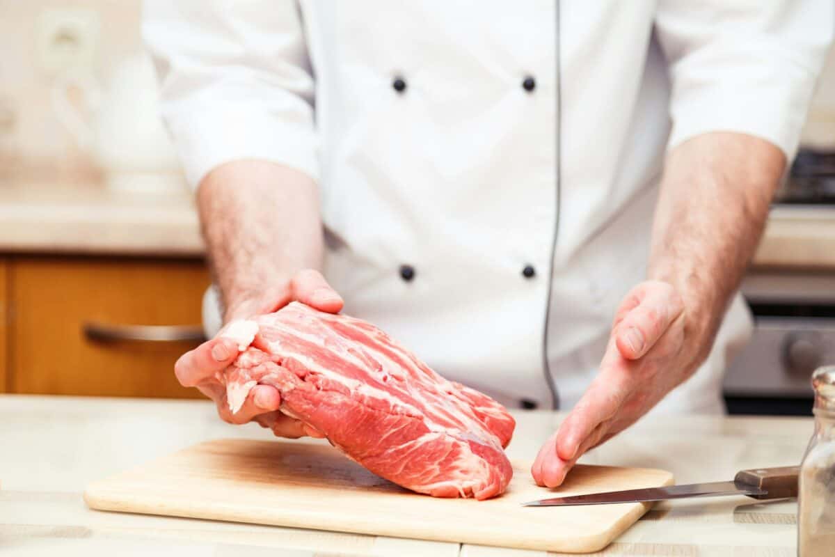 Professional cook men show a piece of meat. Close up