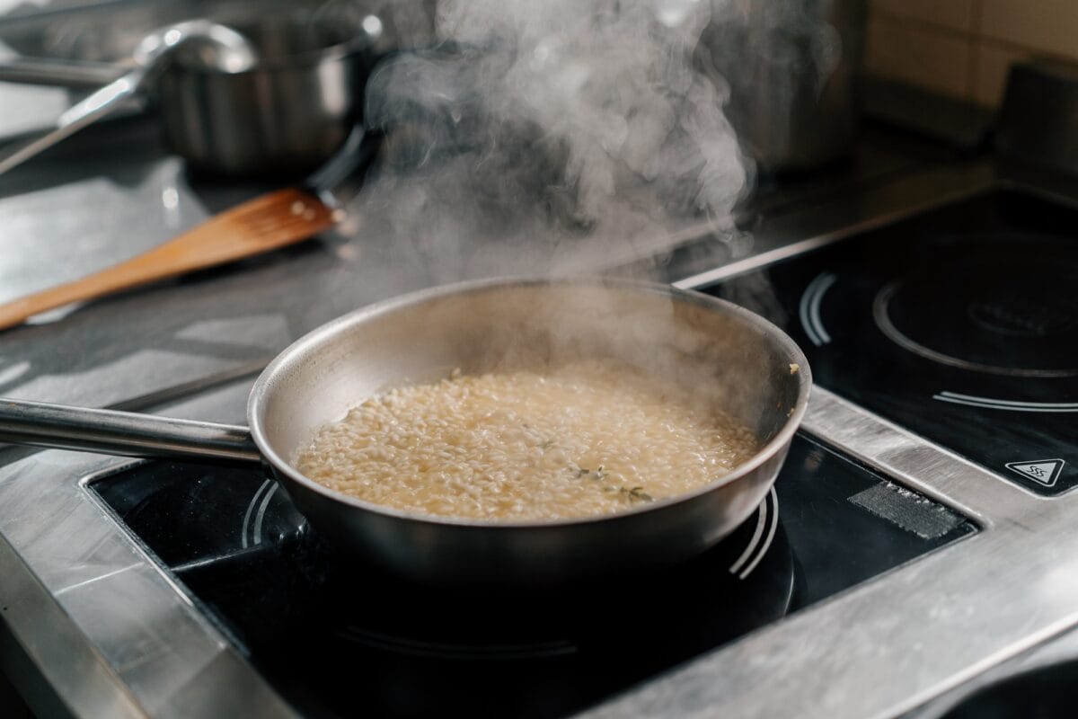 Professional kitchen in the hotel restaurant close-up of chef preparing risotto on the stove