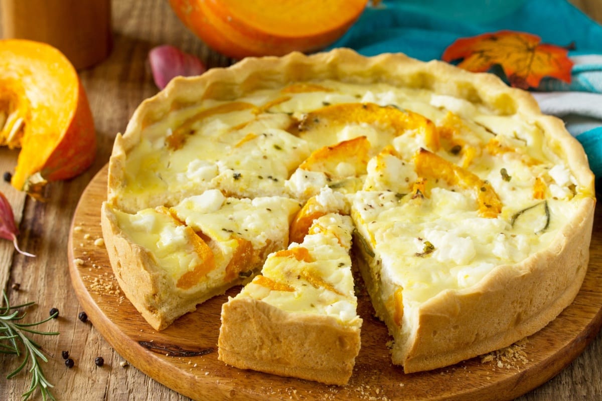 Quiche Lorraine classique au potiron et à la feta sur une table en bois.