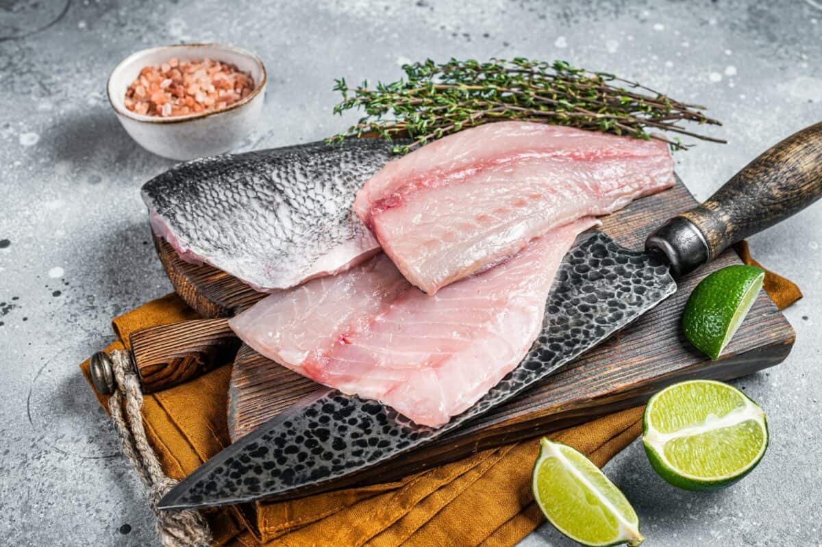 Raw Gilthead Sea bream fish fillets on a butcher cutting board. Gray background. Top view