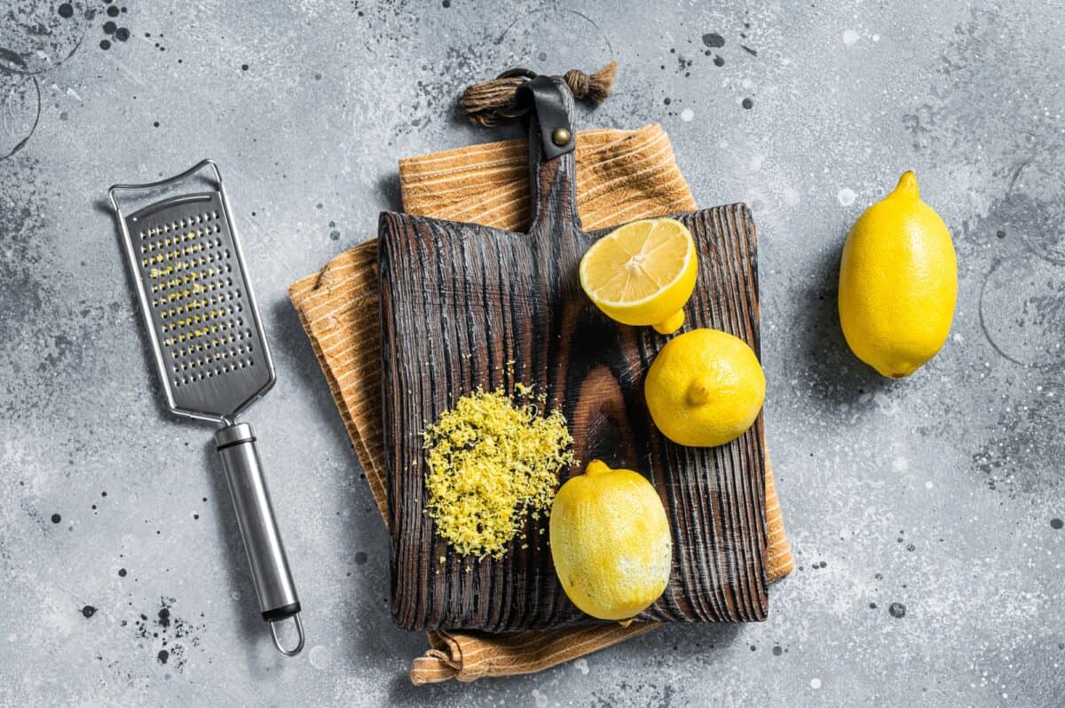 Raw grated Lemon Zest peel on wooden board. Gray background. Top view