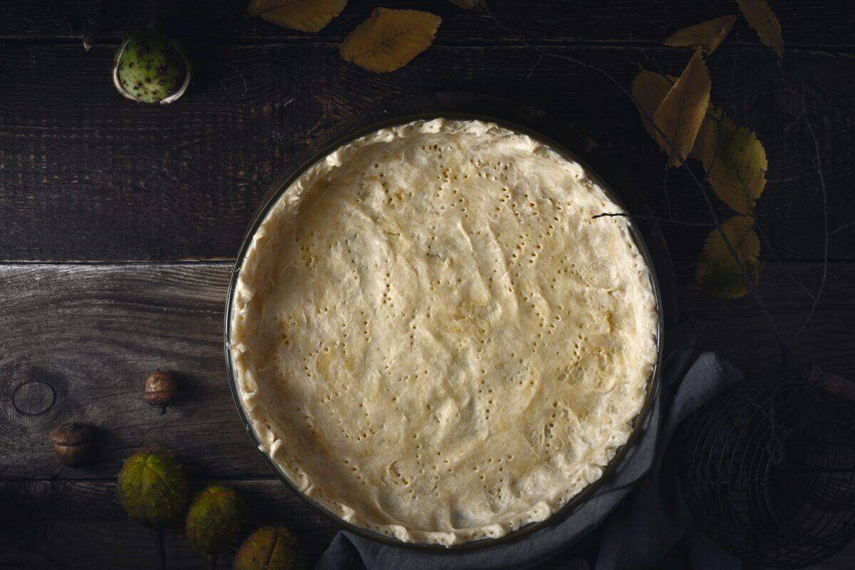 Raw shortcrust pastry in the baking dish on the wooden table top view