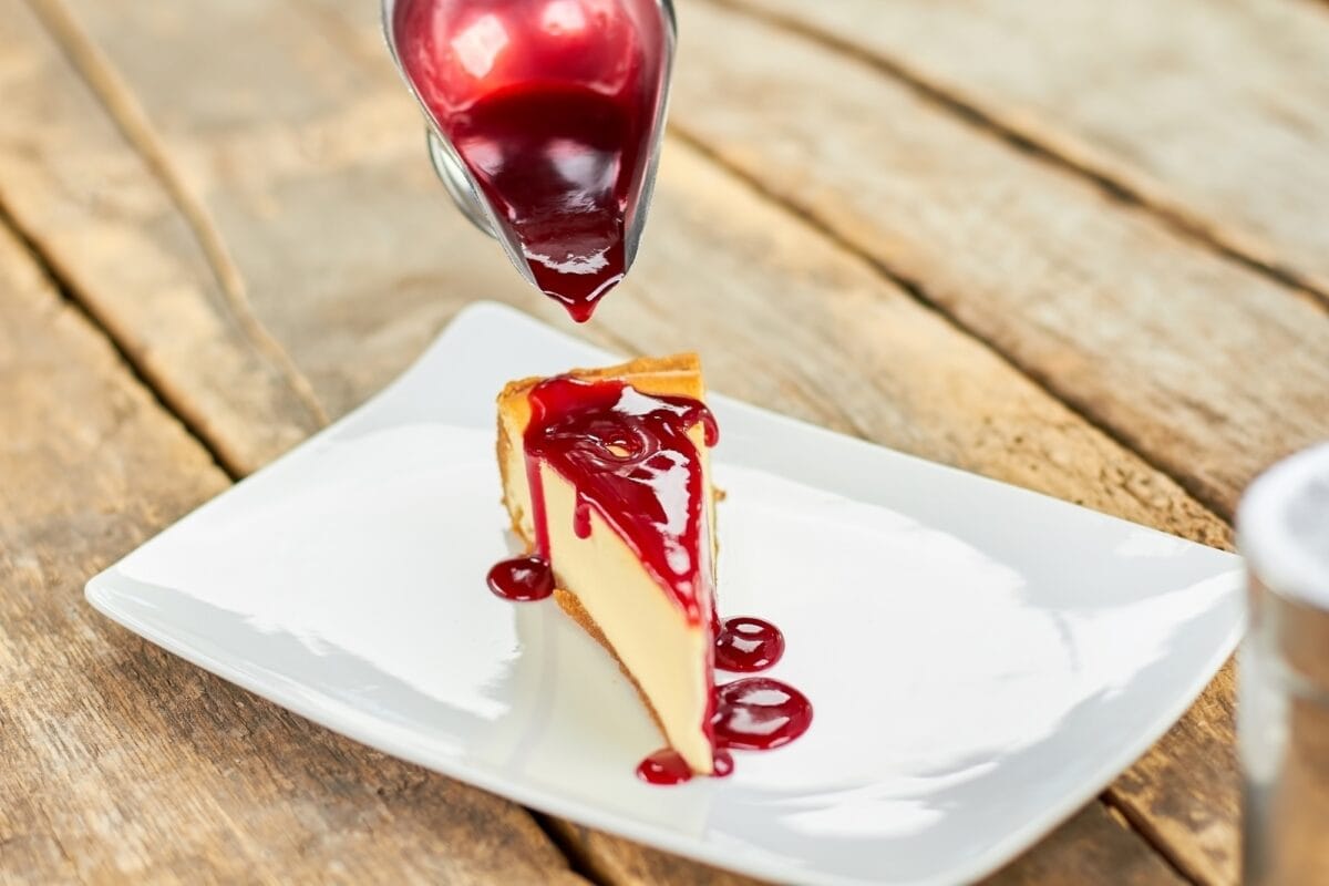 Red strawberry jam pouring cheesecake.
