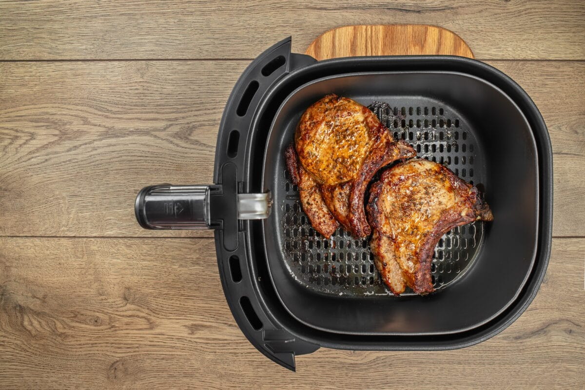 Roast pork steak in airfryer on a wooden table. easy crispy food with little