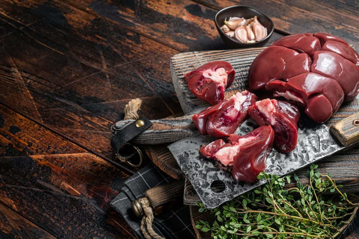 Rognon d'agneau cru, abats frais sur planche de boucherie aux herbes