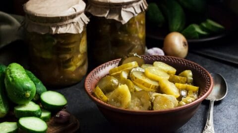 Salade de concombre mariné dans un bol et bocaux sur fond noir