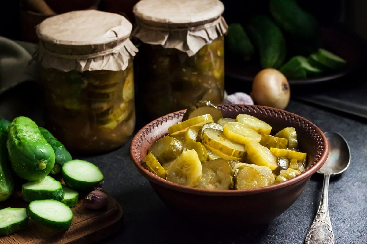 Salade de concombre mariné dans un bol et bocaux sur fond noir