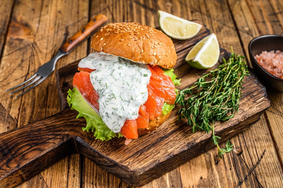 Sandwich with salted fish salmon, avocado, burger bun, mustard sauce and Iceberg salad.