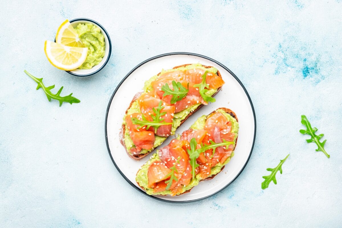 Sandwich ou toast à l'avocat et au saumon sur pain de seigle avec sauce guacamole et jeune roquette