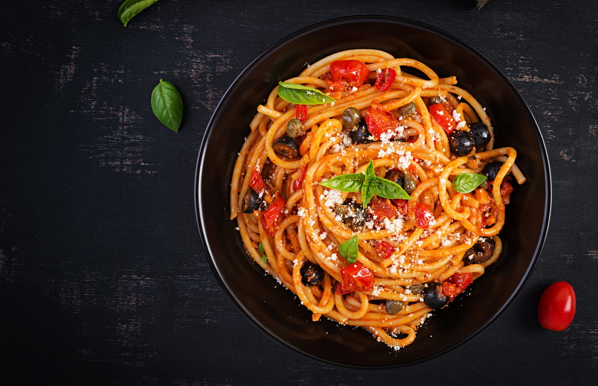 Spaghetti, plat de pâtes italien avec tomates, olives noires et câpres.