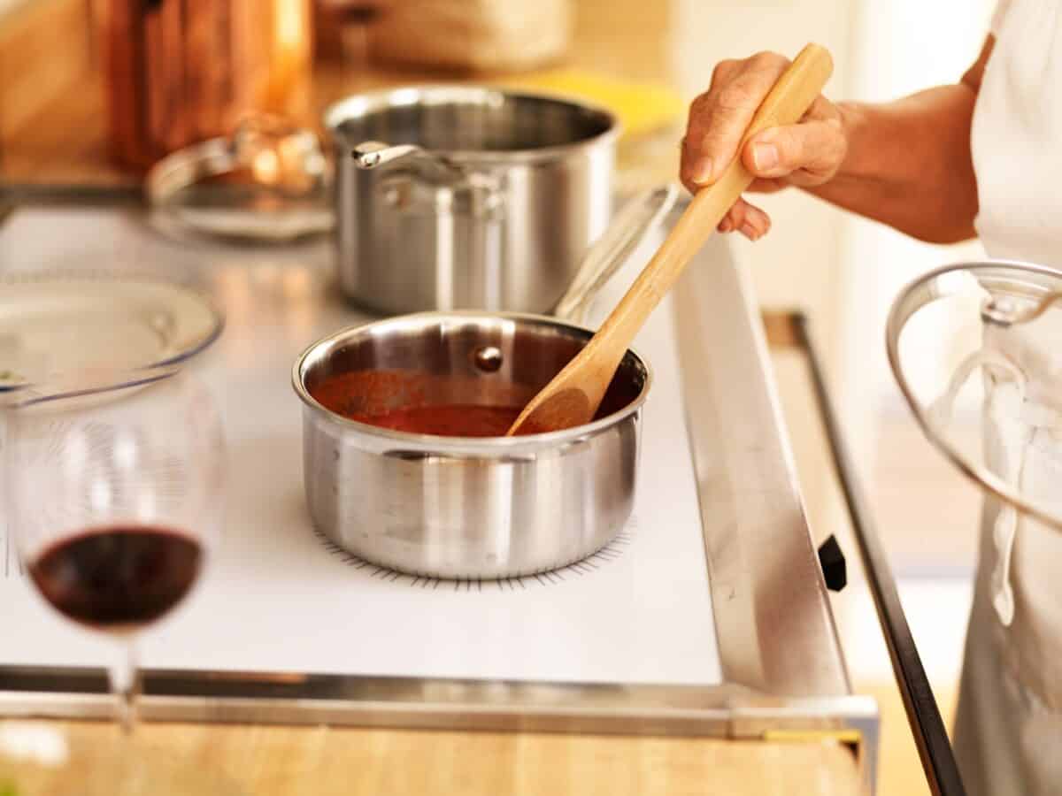 stirring a small pot of spaghetti sauce on the stove