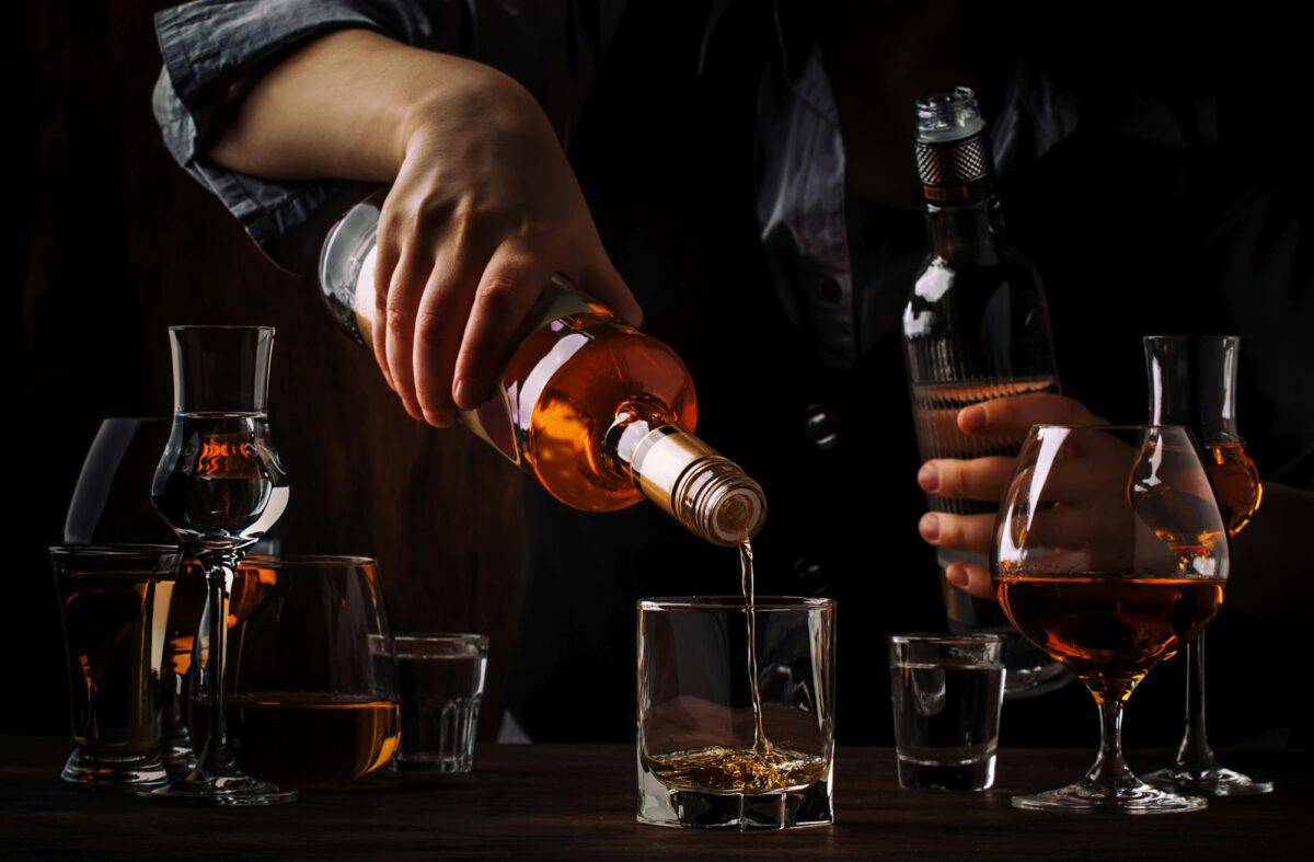 The bartender pours the dark golden rum