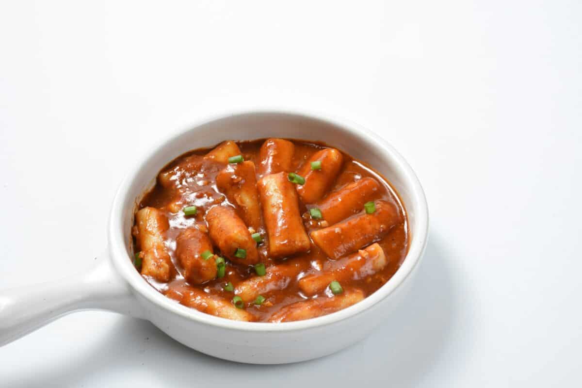 Tteokbokki ou gâteau de riz épicé coréen, l'image d'un délicieux tteokbokki épicé sur fond blanc.
