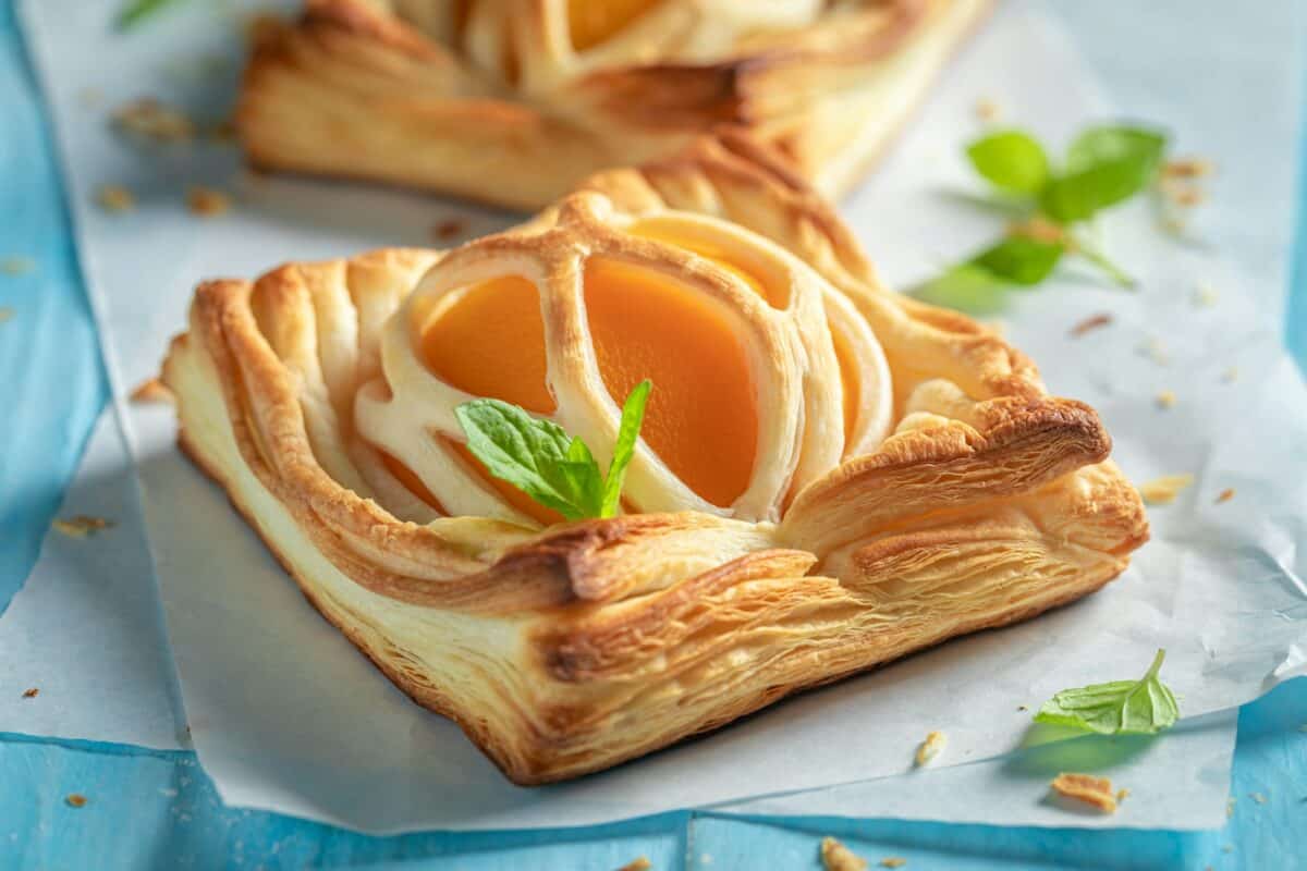 Une superbe pâte feuilletée avec du sucre en poudre et des pêches fraîches