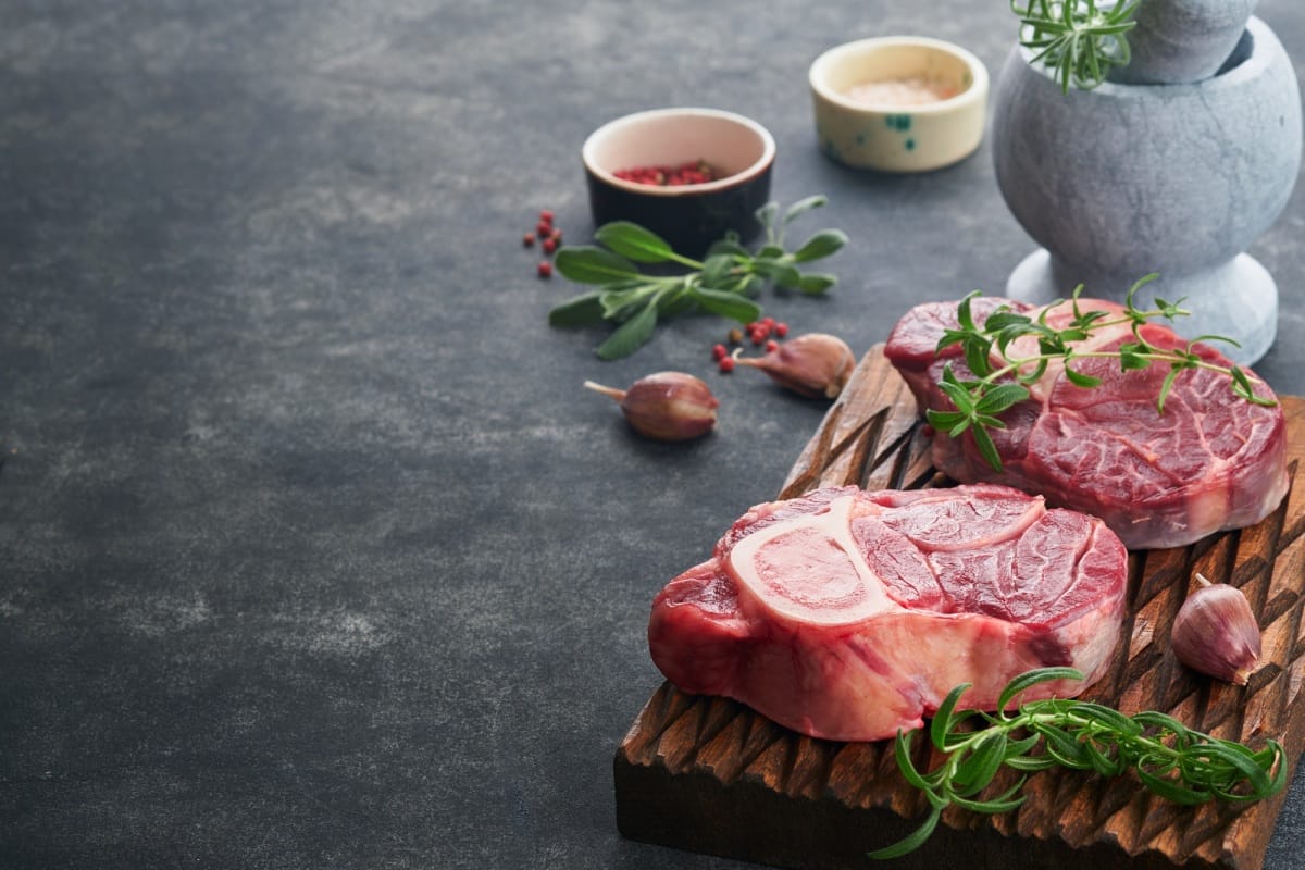 Viande de steak cru Osso Buco. Viande pour barbecue. Jarret de veau frais cru coupé en croix et assaisonnements poivre, romarin.